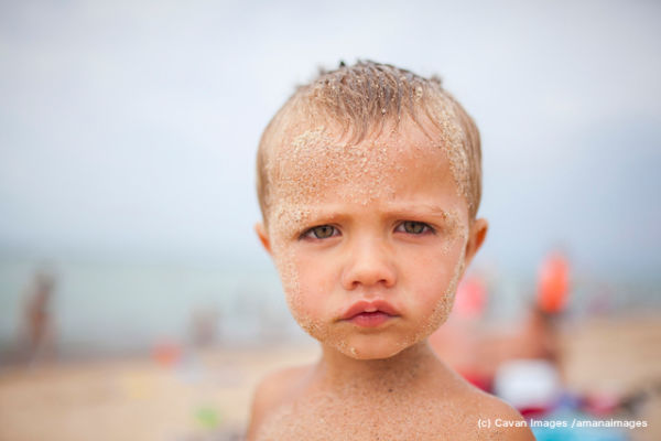 Portrait of messy boy at beach against sky